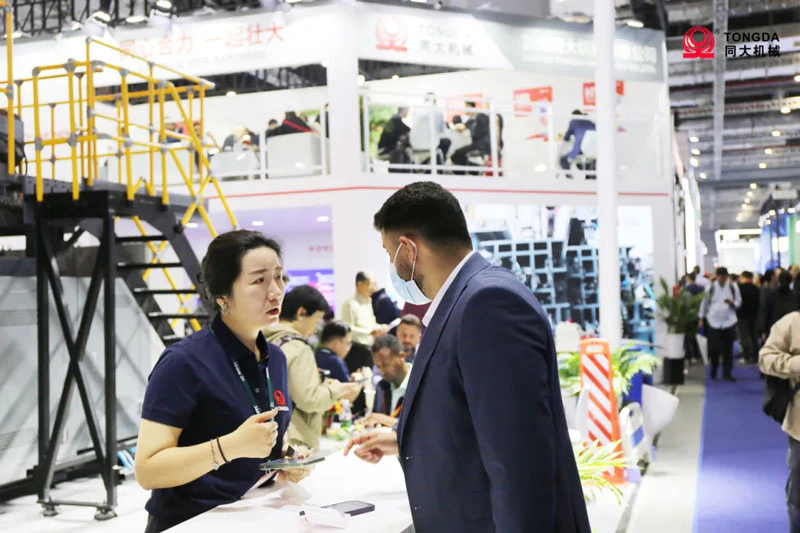 Representante de Tongda conversando con un visitante en CHINAPLAS 2024